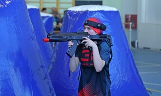 Девушка с оружием LASERWAR за синим надувным укрытием.